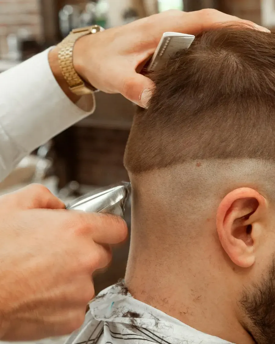 A barber working on a client in a warm shop