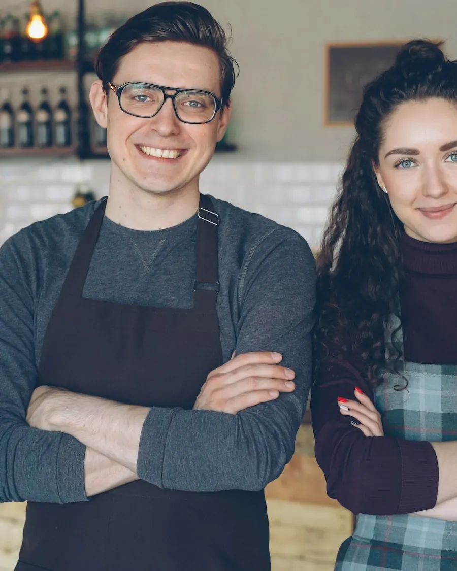 Two cafe owners standing together behind their counter