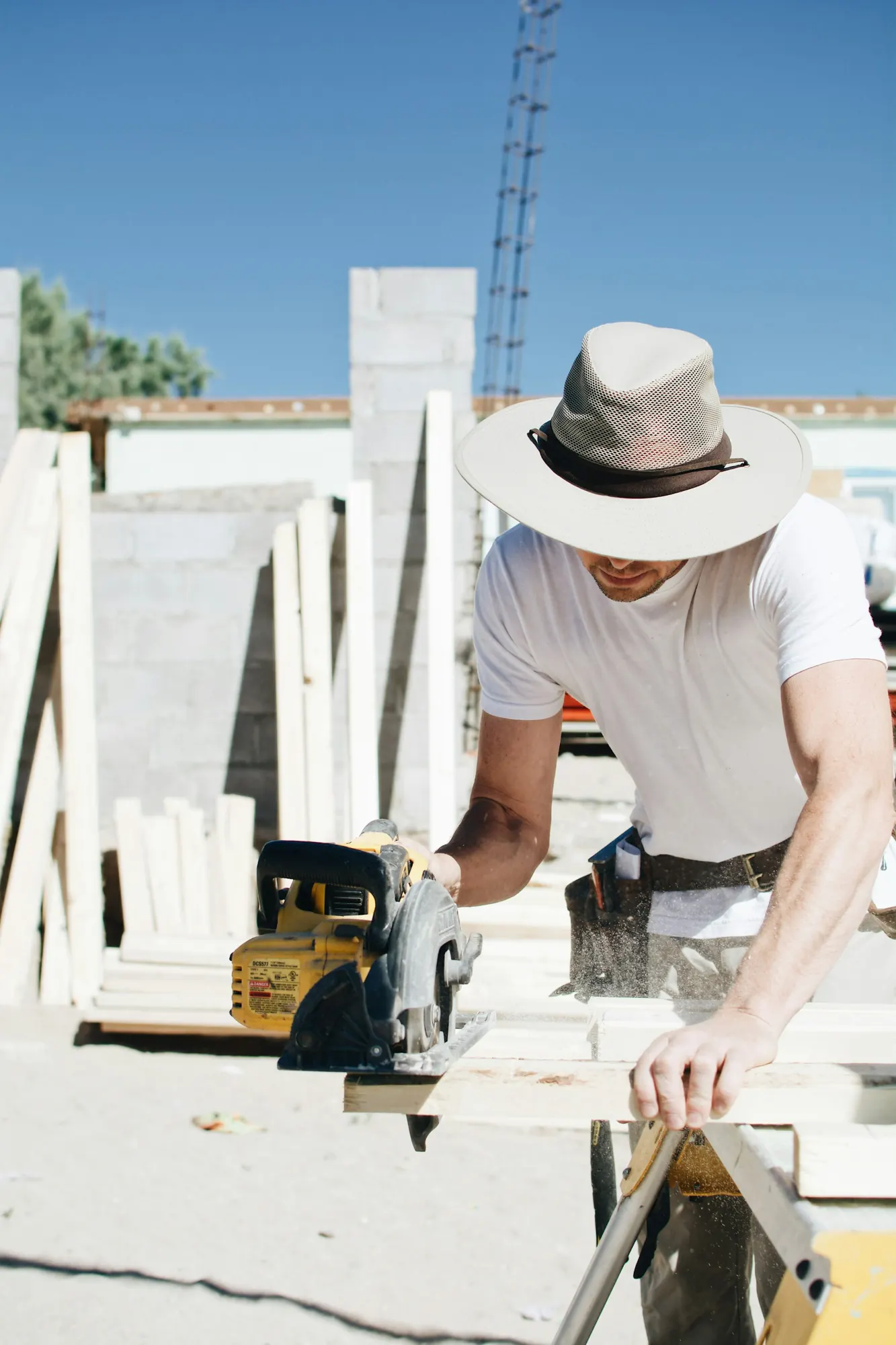 A contractor in a wide-brim hat working at a job site in bright sun