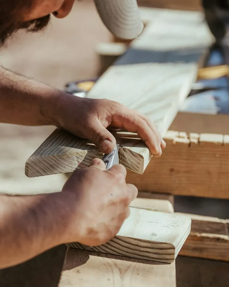 Hands measuring a board at a workbench