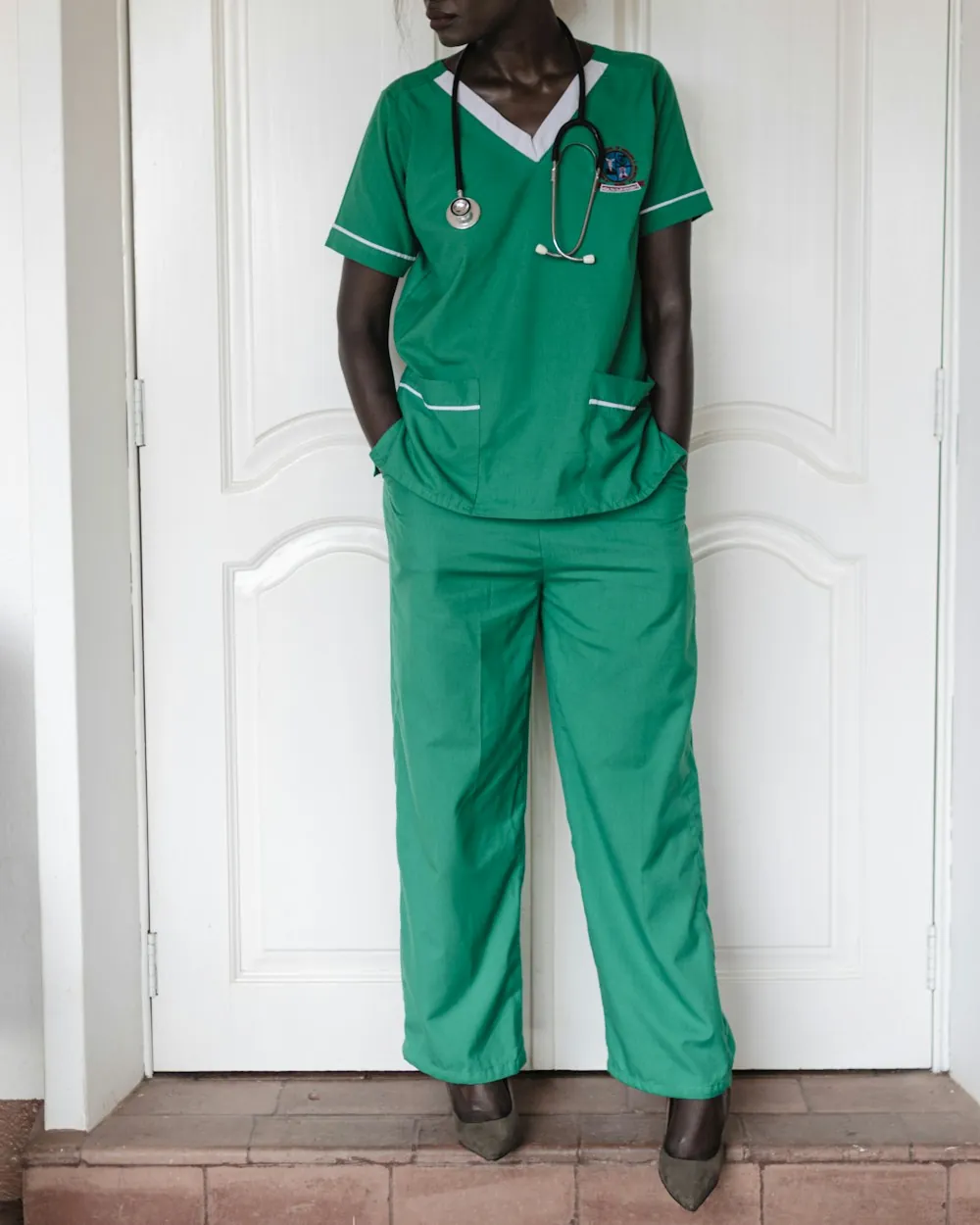 A nurse in green scrubs standing in a doorway