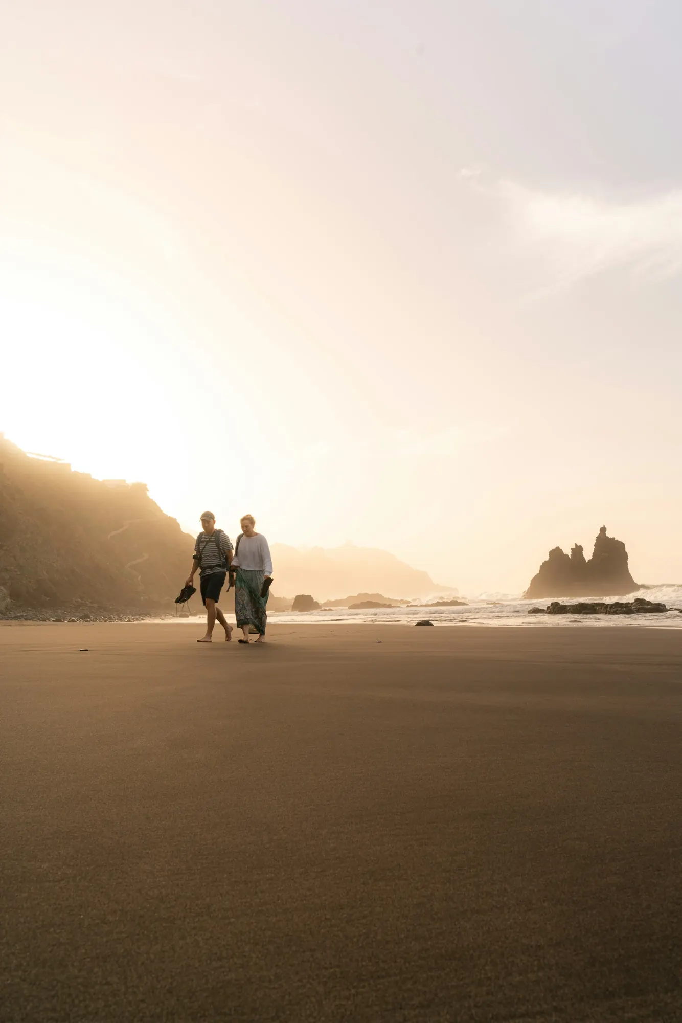A couple walking along a beach at golden hour