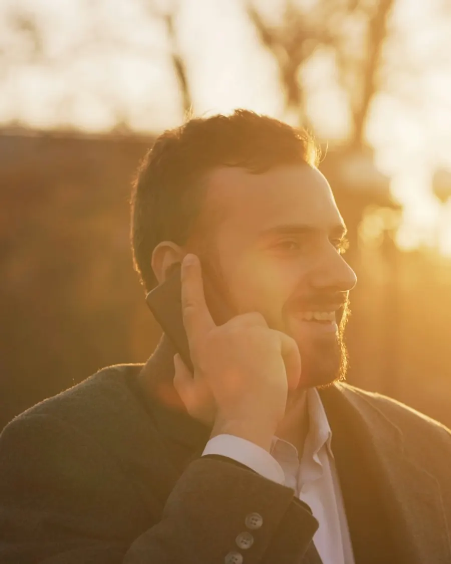 A salesman on the phone outdoors at sunset