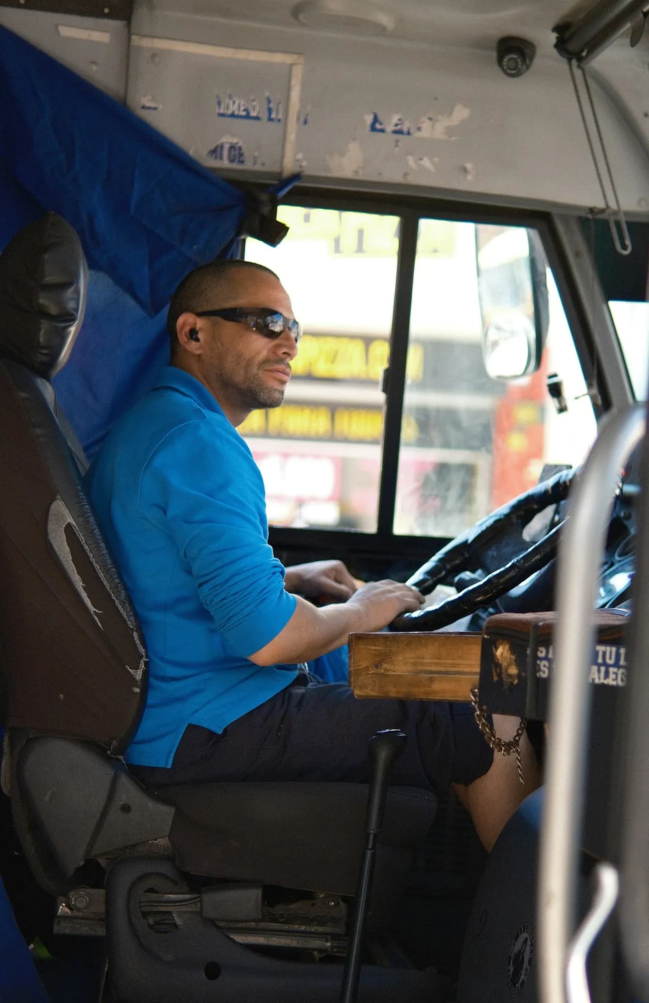 A driver at the wheel of a truck cab, road ahead