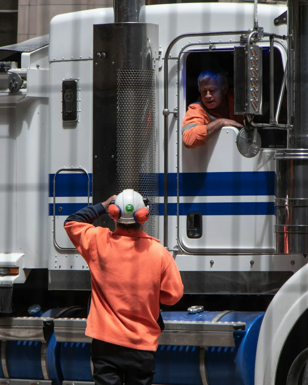 A driver climbing into the cab of a white semi